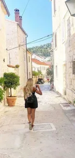 Woman walking on a charming sunny street with stone buildings.