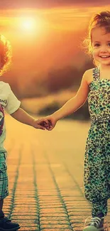 Two children holding hands during a vibrant sunset with a warm, glowing background.