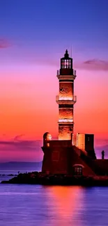 Silhouette of lighthouse against vivid sunset and serene ocean.