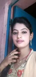 Portrait of a woman in traditional attire, set against a rustic blue doorway backdrop.