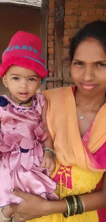 Mother holds child in vibrant village setting.