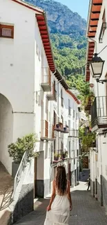 Woman walking down charming village street with mountain backdrop.