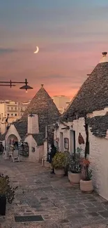 Charming stone village at sunset with crescent moon in background.