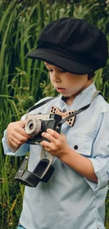 Child in blue shirt holding a vintage camera outdoors.