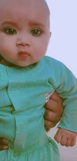 Cute baby wearing green outfit for wallpaper.