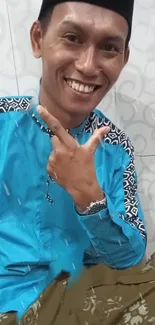 Cheerful man in blue shirt with patterned design smiling.