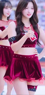 Cheerleaders performing energetically in red attire at a sports event.