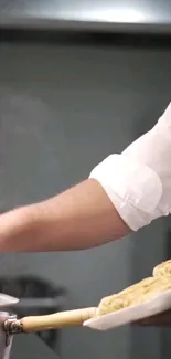 Chef's hands preparing a pasta dish in a professional kitchen setting.