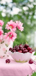Bowl of cherries and pink daisies on a table with pink cloth.