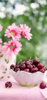 Bowl of ripe cherries with pink flowers in a garden setting.