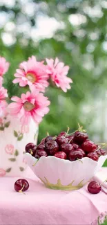 Bowl of cherries with pink flowers on a table.