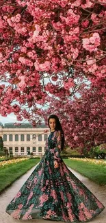 Woman in floral dress under cherry blossoms in a garden path.