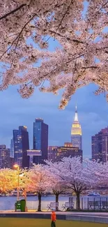 Mobile wallpaper with cherry blossoms and city skyline at twilight.