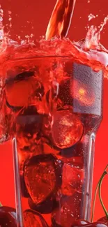 Glass of cherry juice with ice splashing vividly over a red background.