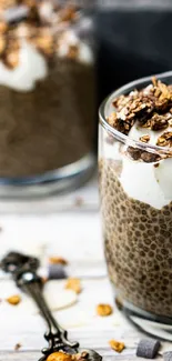 Chia pudding with granola in glass cup on wooden table.