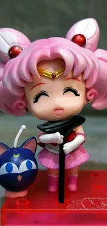 Chibi anime figure toy with pink hair and cheerful expression on a vibrant base.