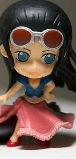 Chibi figurine with sunglasses in pink skirt.