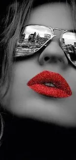 Black and white portrait with red lips and mirrored sunglasses reflecting a city.