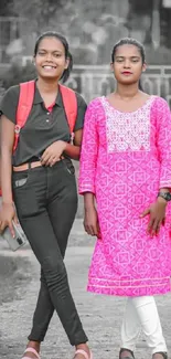 Two friends walking in park, stylish pink attire.