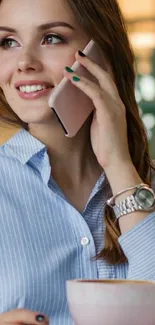 Stylish woman holding phone with coffee, light blue shirt.