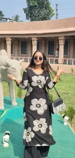 Woman in floral dress standing outdoors near statue.