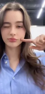 Woman winking with peace sign, blue shirt.