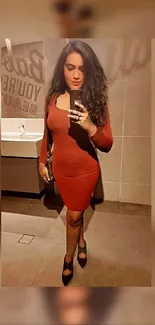 Woman in a chic red dress taking a mirror selfie.