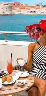 Woman in red hat enjoying brunch by the sea with coastal view.