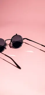 Round sunglasses on pink background mobile wallpaper.