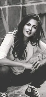 Black and white urban portrait of a young woman in casual attire crouching elegantly.