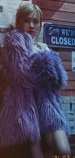 A person in a purple fur coat stands by a closed sign in an urban setting.