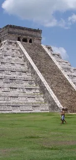 Chichen Itza pyramid under a blue sky with green grass.