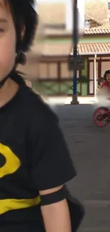 Child rides bike in urban area wearing a Batman T-shirt.