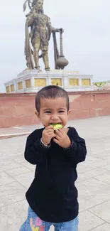 Child smiling in front of a large statue.