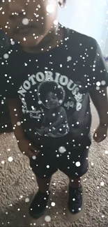 Child wearing black t-shirt with snow effect on wallpaper.