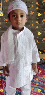 Child in white traditional attire with floral background.