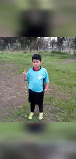 Boy in a sports uniform standing in a field.