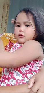 Child wearing floral dress in warm hues.