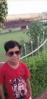 Wallpaper of a child wearing sunglasses in a garden with a green background.