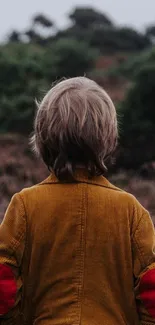 Child with mustard jacket in nature landscape.