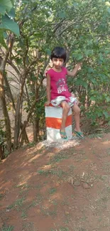 Child sitting in nature, surrounded by greenery and trees.