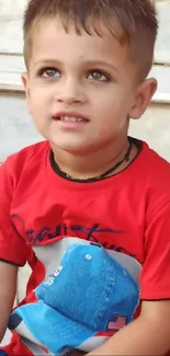 Young child in red shirt sitting, smiling on steps.