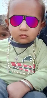 Child wearing sunglasses in a stylish outdoor setting.