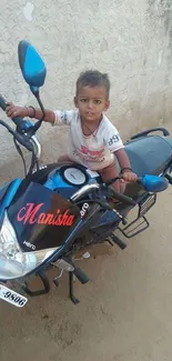 Child sitting on a blue motorcycle, outdoor setting.