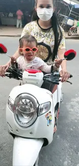 Child wearing sunglasses on a white scooter.