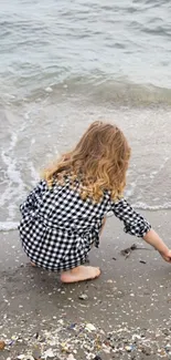 Child playing by the sea with shells on the shore.