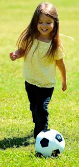 Young girl joyfully playing soccer on lush green grass.