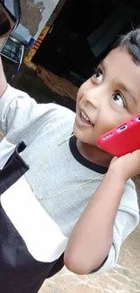 Child enjoying a red smartphone outdoors.