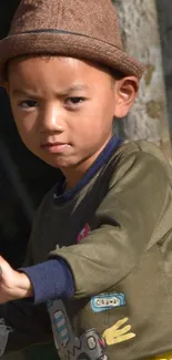 Child in a brown hat rides a toy bike outdoors.