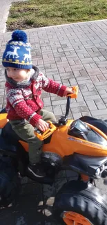 Child on a toy ATV enjoying a sunny day outdoors.